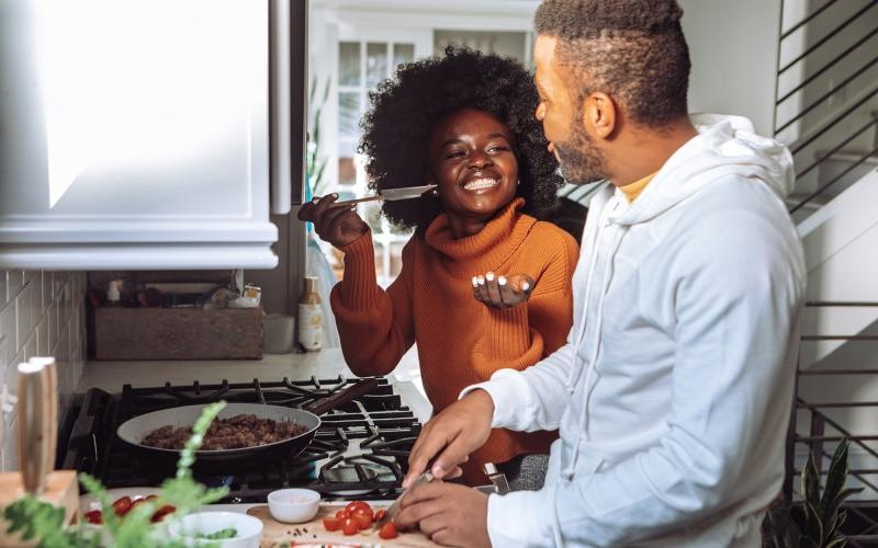 a man and a woman cooking on a gas stove top