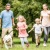 family runs through park with a dog